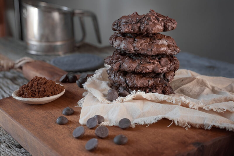 A tall pile of chocolate cake mix cookies stacked on a plate, showcasing their soft and chewy texture.