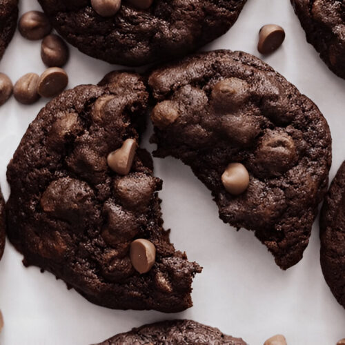 A close-up of a broken chocolate cake mix cookie, revealing its soft and gooey interior filled with chocolate chips