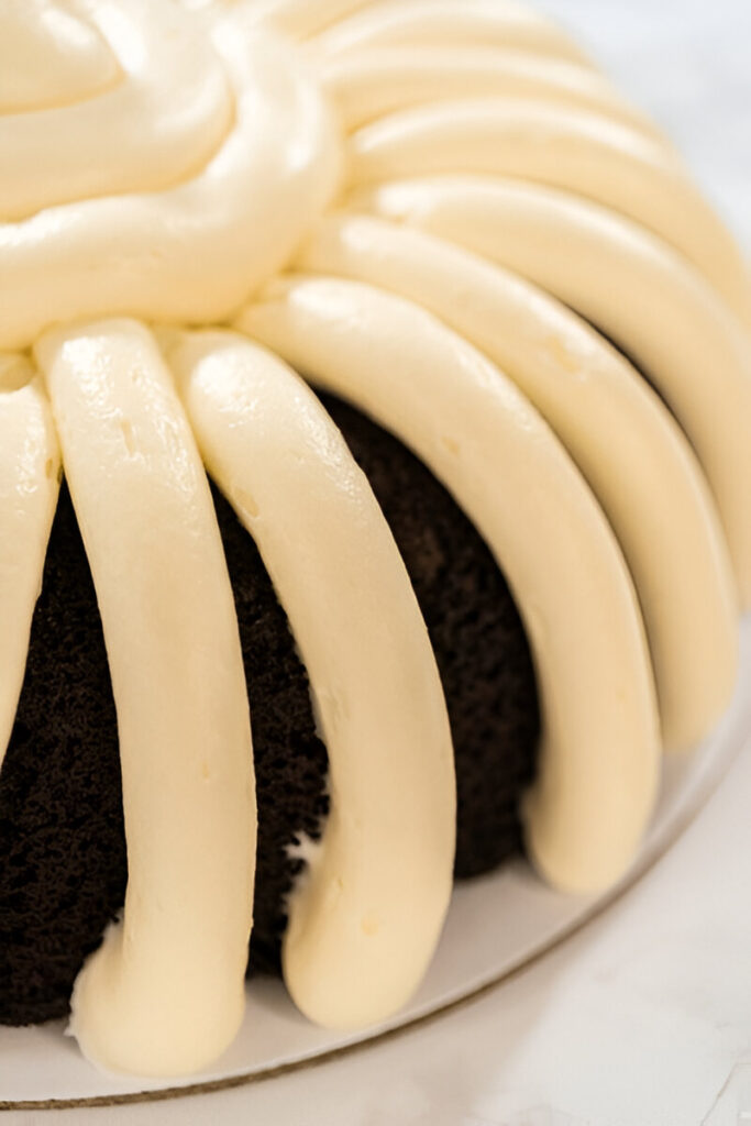 lose-up of cream cheese frosting piped in symmetrical patterns on a nothing bundt cakes.