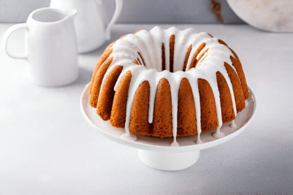 Gluten-free bundt cake with creamy frosting on a white plate.