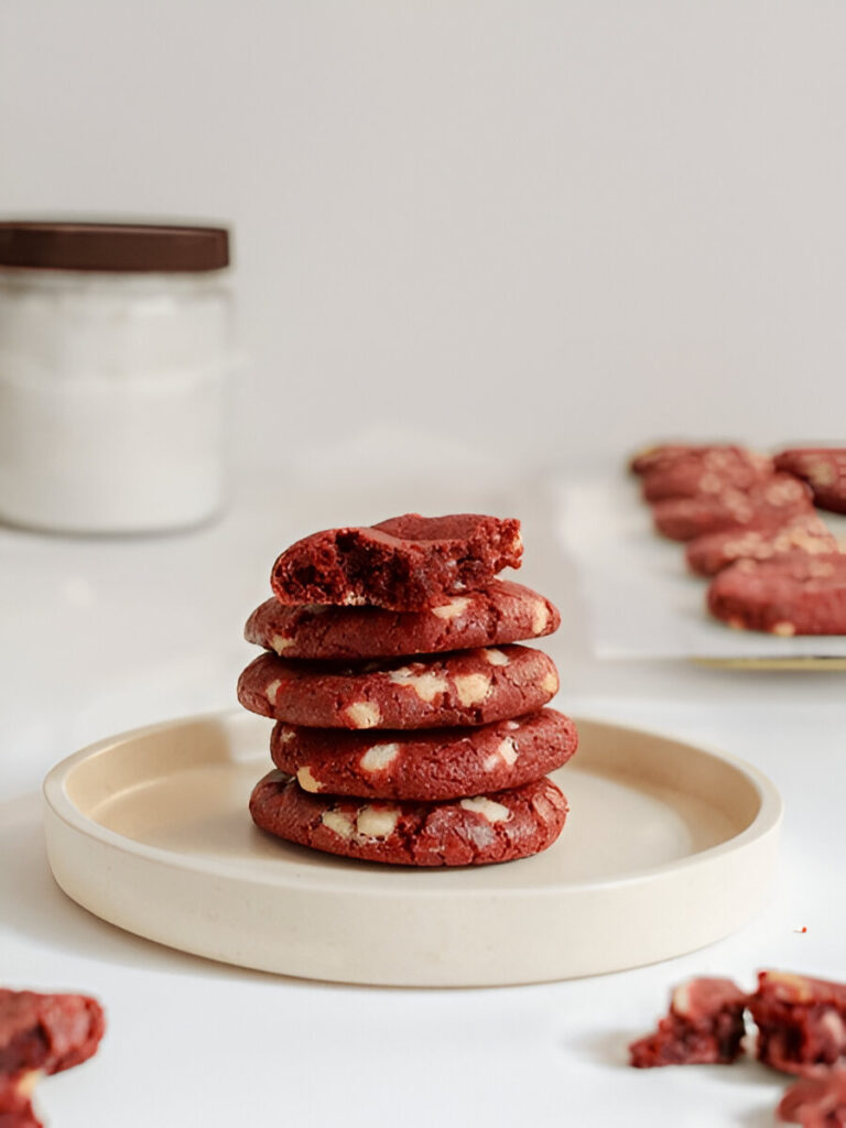 Close-up of red velvet cake mix cookies stacked, with one bitten to reveal the chewy inside.