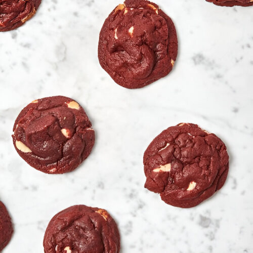 A pile of freshly baked red velvet cake mix cookies on a kitchen counter.