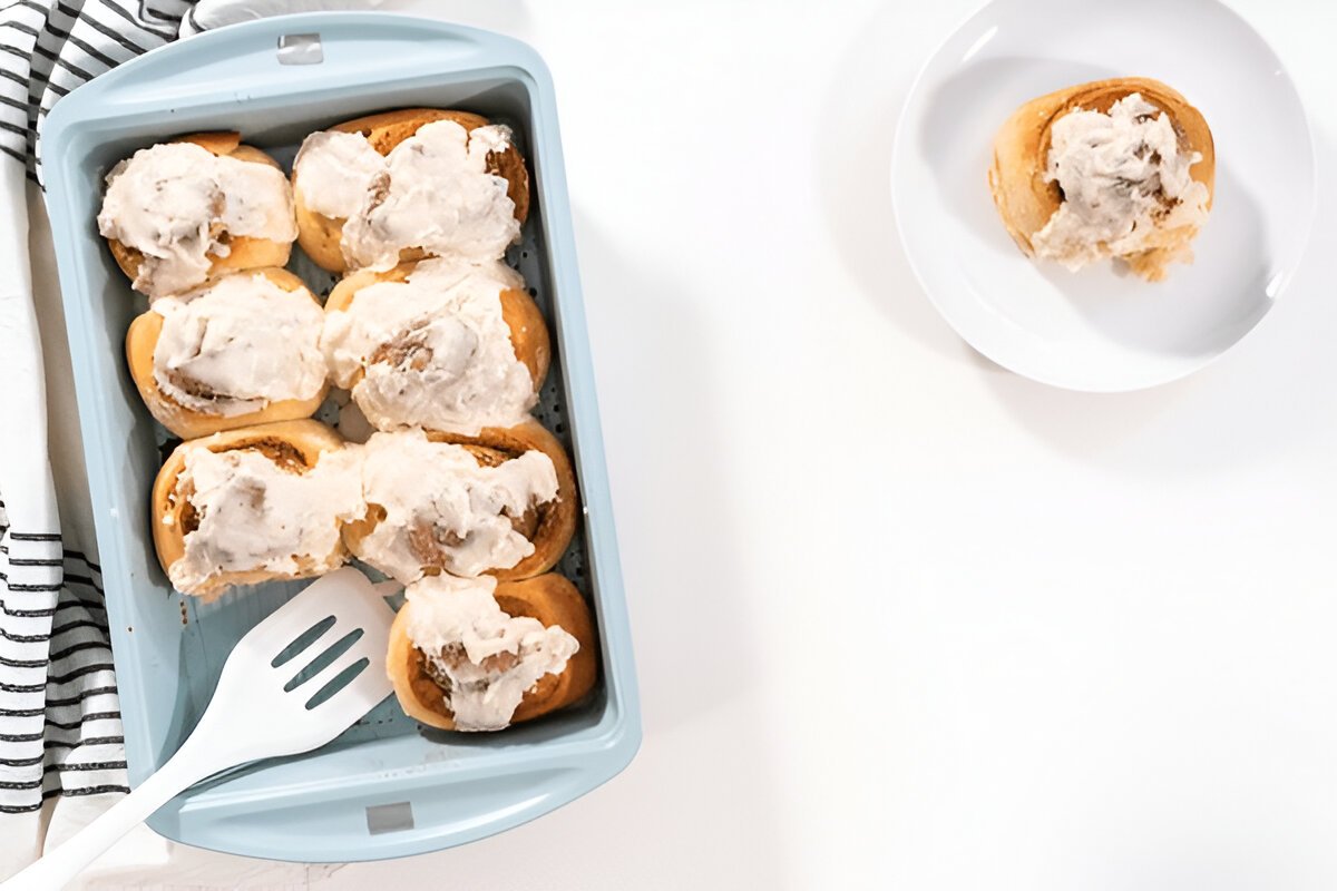 Freshly baked sourdough cinnamon rolls with a creamy glaze in a baking dish.