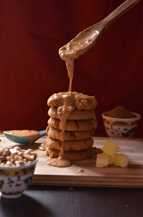 A stack of peanut butter cake mix cookies with a spoon of creamy peanut butter dripping over the top.