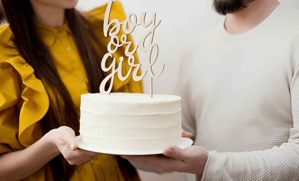 A white frosted gender reveal cakes with smooth icing, topped with gold topper